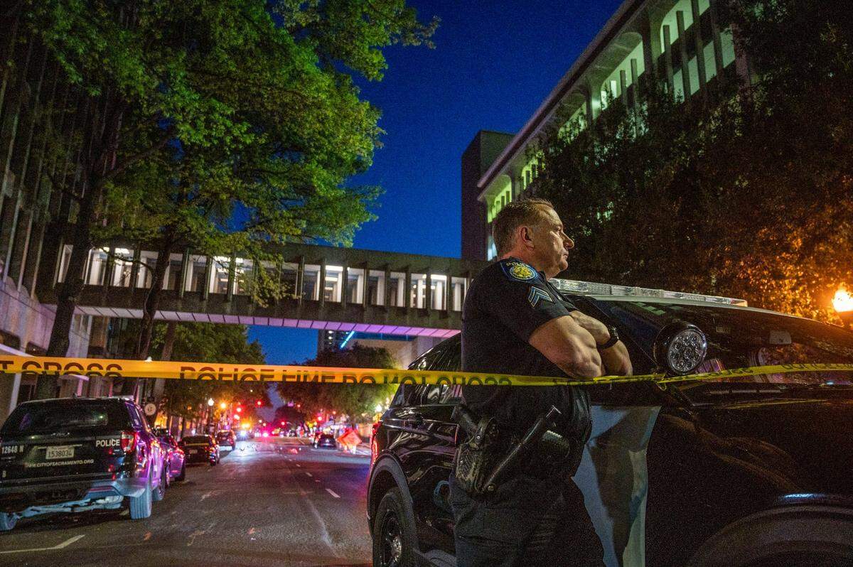 Sacramento Police officer&nbsp;David Bell stands watch at the scene of a mass shooting at 10th and L streets in downtown Sacramento on Sunday, April 3, 2022.