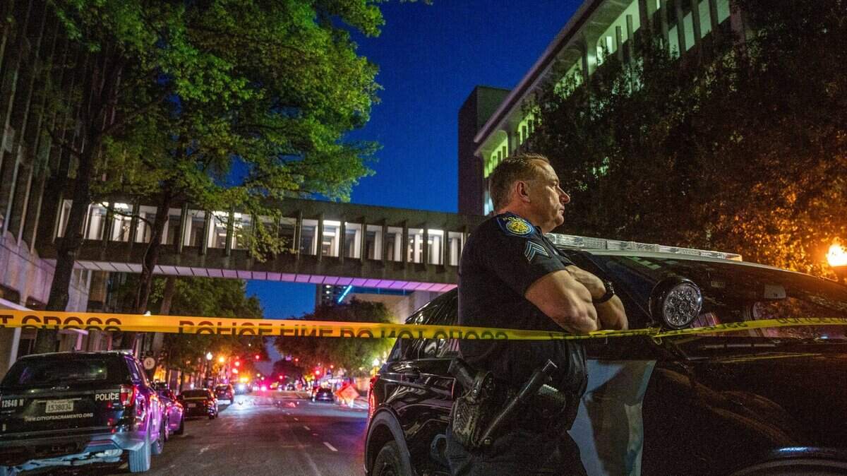 Sacramento Police officer David Bell stands watch at the scene of a mass shooting at 10th and L streets in downtown Sacramento on Sunday, April 3, 2022.