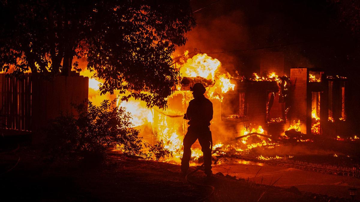 A firefighter hoses down a burning home on Ridge Drive during the Carr Fire in Redding on July 26, 2018.