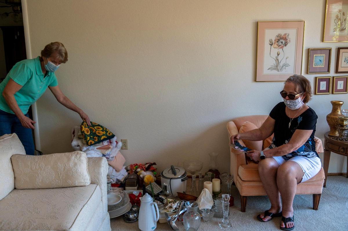 Donna Scully, right, holds a picture of her parents Don and Geraldine “Gerry” Warren, as her sister Patti Warren, left, helps sort through their belongings on Thursday, July 9, 2020, at their childhood home in Esparto. Their parents passed away at age 89 at Stollwood Convalescent Hospital in Woodland. Geraldine died on March 8 from complications of Alzheimer’s disease and Don died on April 16 from COVID-19 complications.