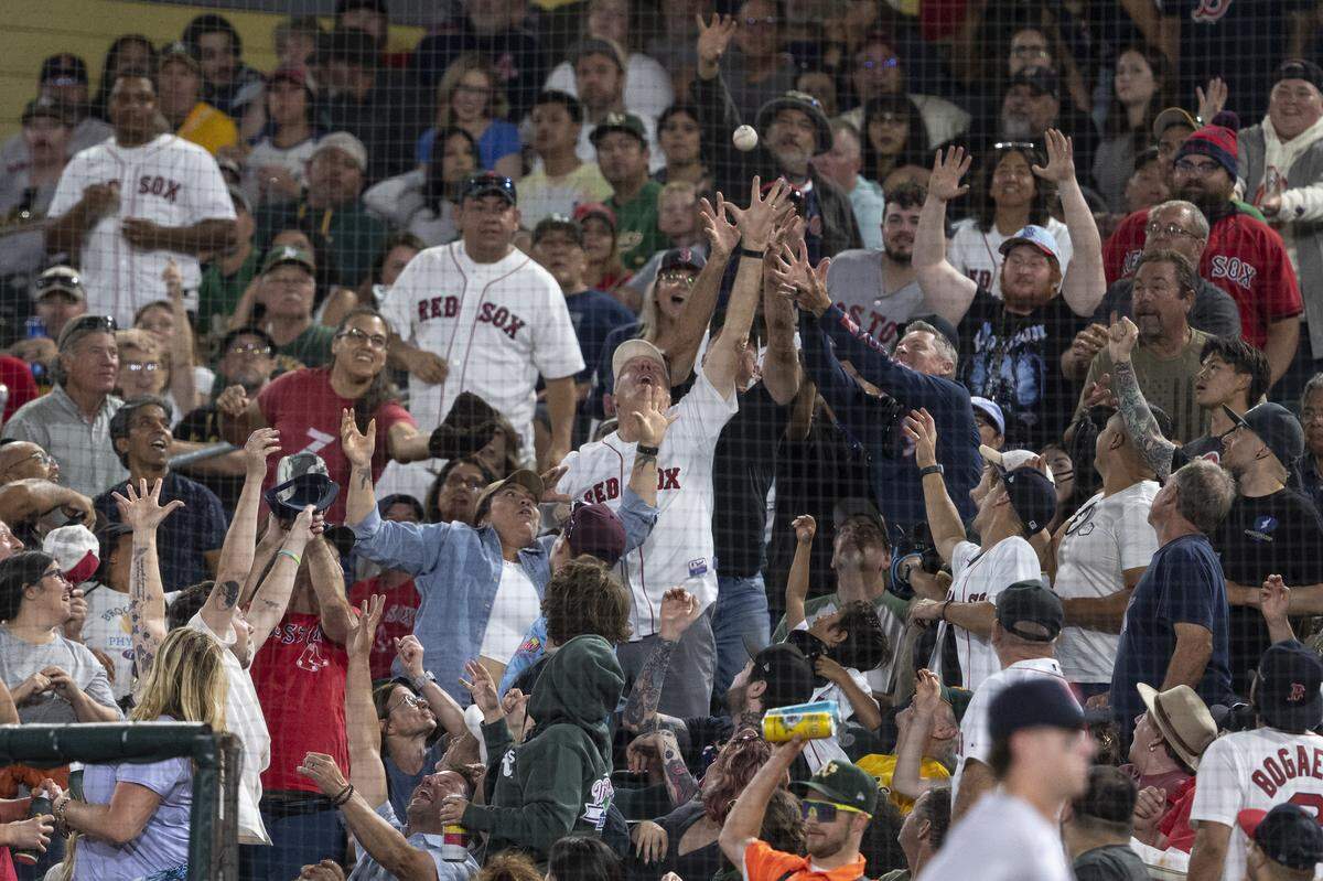 Red Sox fans catch a foul ball during a game between the Athletics and the Red Sox at Sutter Health Park in West Sacramento on Monday.