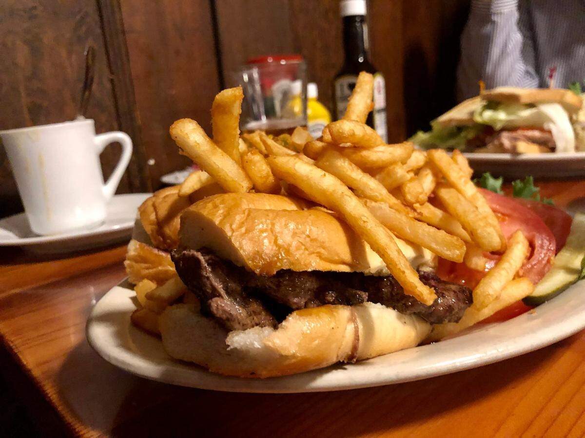 Jamie’s Broadway Grille’s garlic steak sandwich, topped with fries.