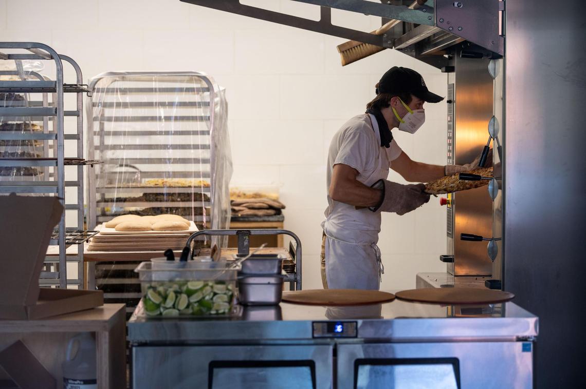 Alex Sherry moves a pizza in the oven at Majka Pizzeria & Bakery in midtown Sacramento on Friday, July 10, 2020. He and his wife, Chutharat Sae Tong, opened the new business in late June, but made the decision to exclusively serve takeout and delivery for safety reasons amid the coronavirus pandemic.