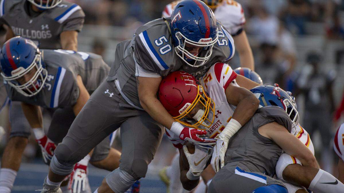Folsom Bulldogs defensive lineman Caleb Freeland (50) stops Jesuit Marauders Isaiah Rutherford after a one-yard gain on Aug. 24.