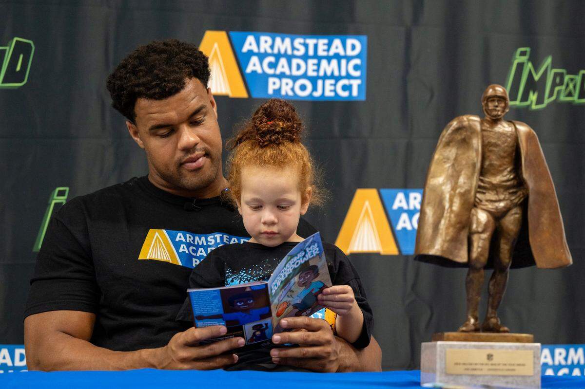 Arik Armstead reads “Discovering My Superpower,” a comic book he created that reflecting his personal journey, to his daughter Ayla, 3, on Friday before a book signing at Impound Comice in Sacramento. The book aims to inspire youth through literacy and empowerment.