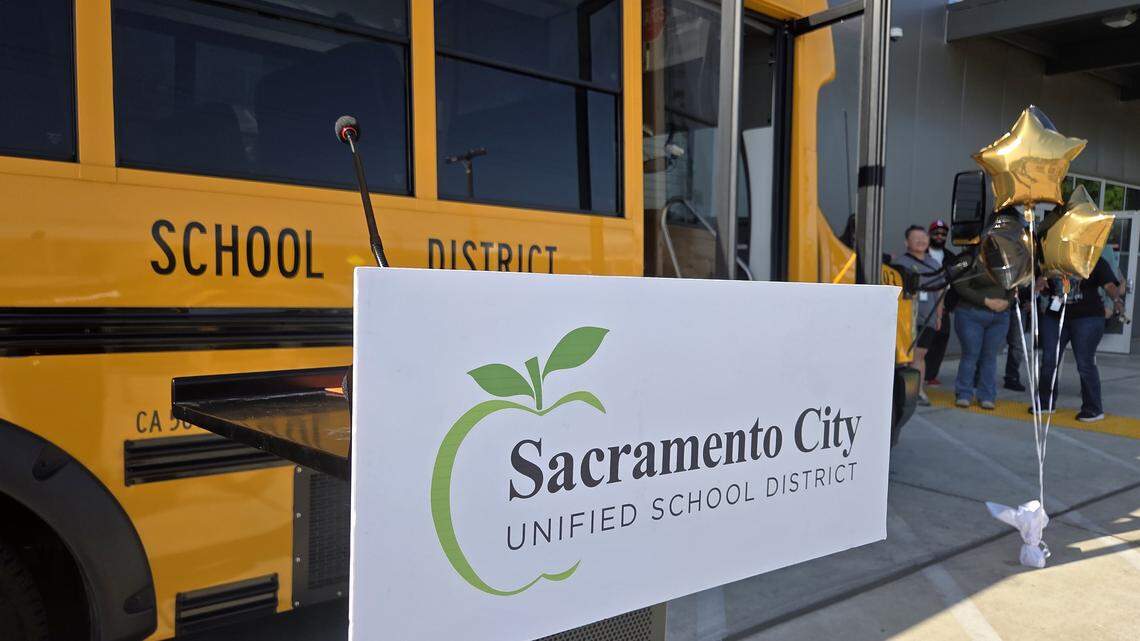 A podium with the Sacramento City Unified School District logo stands in front of an electric bus during an event celebrating National School Bus Driver Appreciation Day at the SCUSD Transportation Department on Tuesday. Chamberlain Segrest, the district’s sustainability manager, said she hopes to see 80% of the district’s school bus fleet become electric within the next five years.