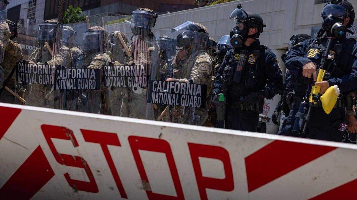California National Guard troops stand outside the Metropolitan Detention Center in downtown Los Angeles on Sunday amid protests against federal immigration raids. The troop presence followed President Donald Trump’s directive to send 4,000 Guard members and 700 Marines to the city over the objections of Gov. Gavin Newsom, who has challenged the legality of the deployment in federal court.