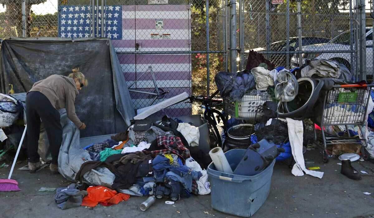 A woman camping in downtown San Diego sorts through her belongings in 2017. Homeless residents of downtown San Diego encampments will be paid to pick up trash in their neighborhood as part of a new pilot program.
