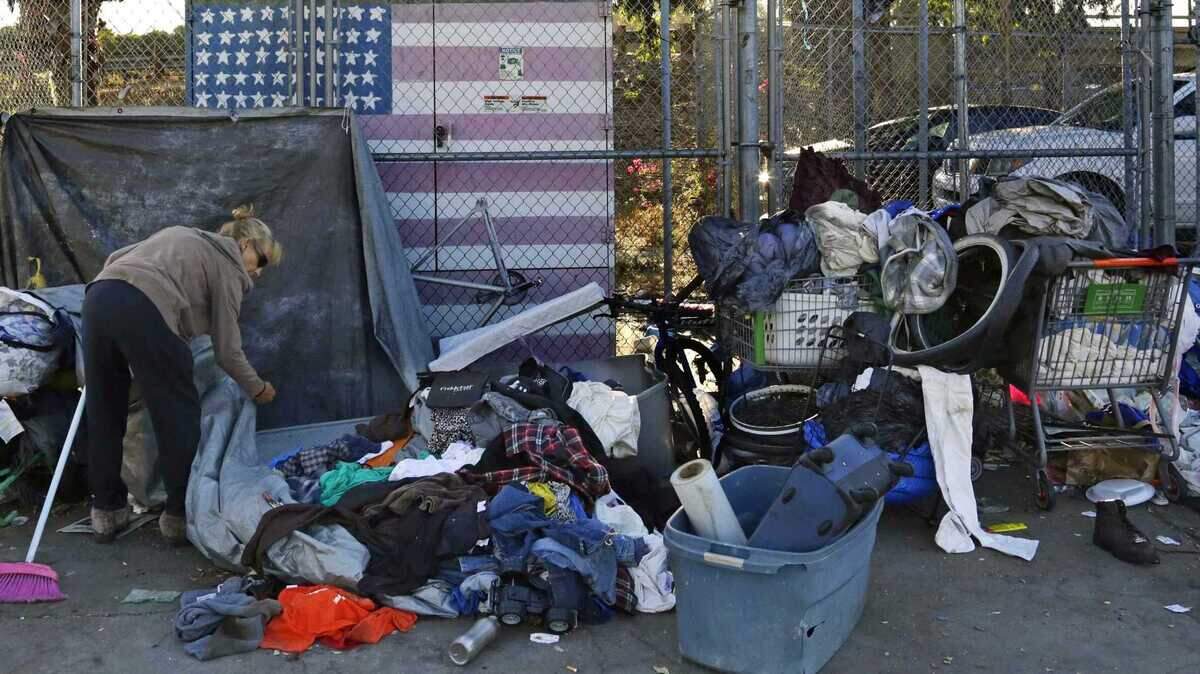A woman camping in downtown San Diego sorts through her belongings in 2017. Homeless residents of downtown San Diego encampments will be paid to pick up trash in their neighborhood as part of a new pilot program.