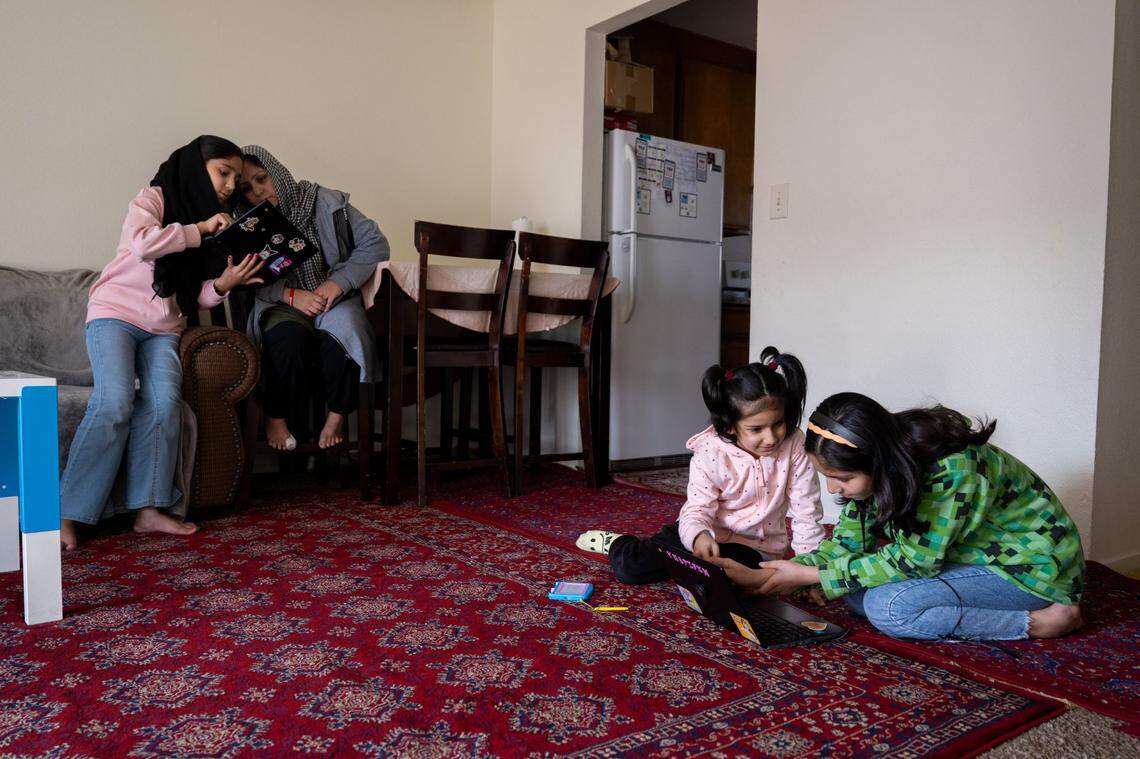 Zakia Ahmadi, 13, shows a school lesson on her computer to mother Marzia Ahmadi, as sisters Zohra, 12, and Bahara, 7, look at a lesson on a laptop in their sparsely furnished Yuba City apartment in January. 