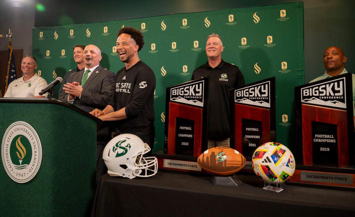 Sacramento State President Luke Wood, center, laughs while standing with coaches and athletic director Mark Orr, at a press conference Thursday, Sept. 26, 2024, to announce their plan for a new football stadium scheduled to be completed for the 2028 season.