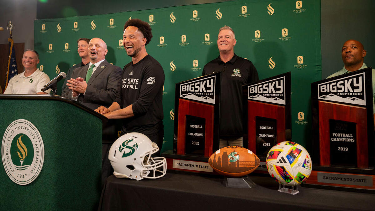 Sacramento State President Luke Wood, center, laughs while standing with coaches and athletic director Mark Orr, at a press conference Thursday, Sept. 26, 2024, to announce their plan for a new football stadium scheduled to be completed for the 2028 season.