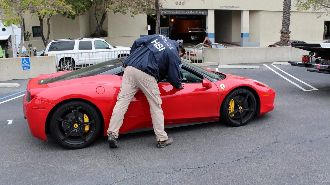 This photo provided by U.S. Immigration and Customs Enforcement shows a special agent with HSI Los Angeles’s El Camino Real Financial Crimes Task Force seize a Ferrari from an Orange County businessman on Friday, April 7, 2021 Santa Ana, Calif. Mustafa Qadiri, 38, of Irvine, was named in a federal grand jury indictment and has pleaded not guilty to charges he obtained $5 million in federal coronavirus-relief loans for phony businesses and then used the money for lavish vacations and to buy a Ferrari, Bentley and Lamborghini, prosecutors said Monday, May 10. (U.S. Immigration and Customs Enforcement via AP)