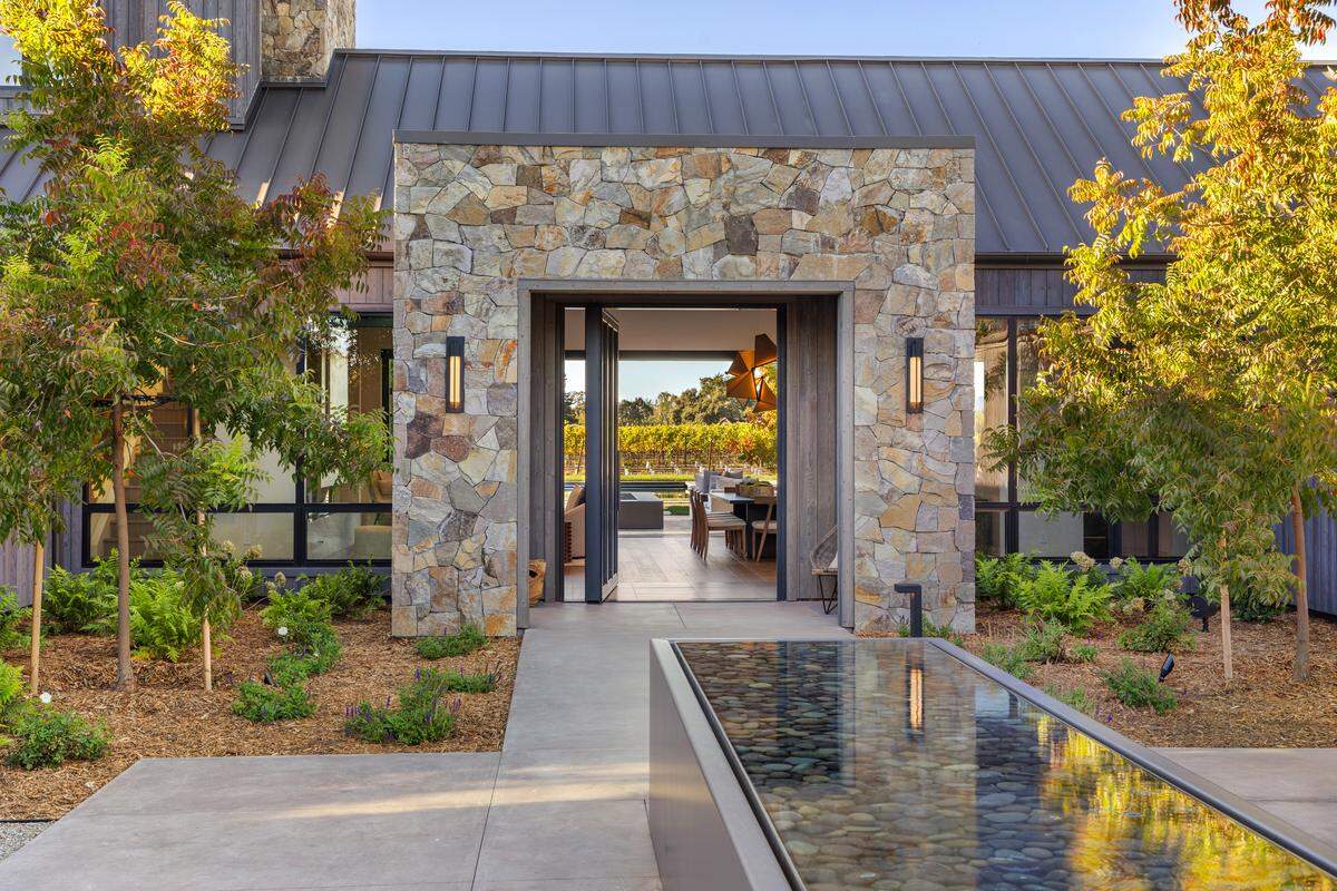 A dramatic entrance welcomes guests with dual gated drives, a grand motor court centered on an ancient olive tree, and striking water features that set the tone for luxury throughout the estate.