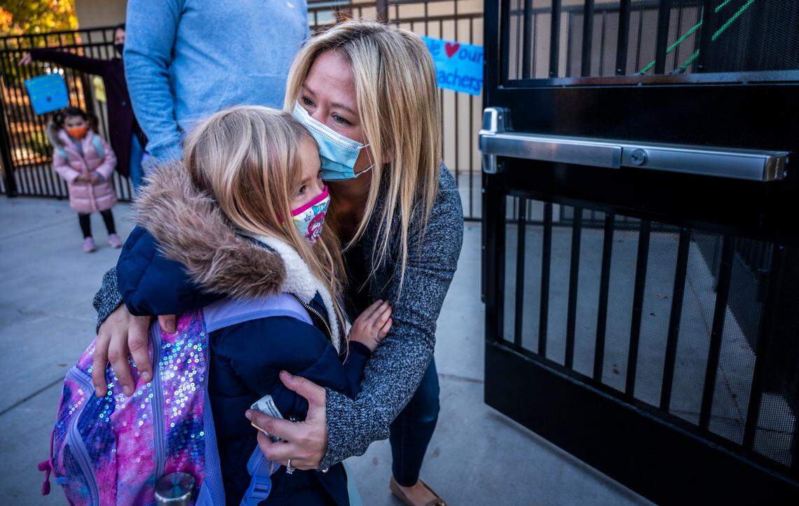 Melanie Ely kisses her daughter Madison, a kindergartener at Folsom Hills Elementary School, before she enters the gates to her class on Thursday, Nov. 12, 2020. It was the first day of school for students the Folsom Cordova Unified School District, the largest district in Sacramento County to reopen for in-class instruction. Parents were not allowed to step foot onto campus due to coronavirus protocols.