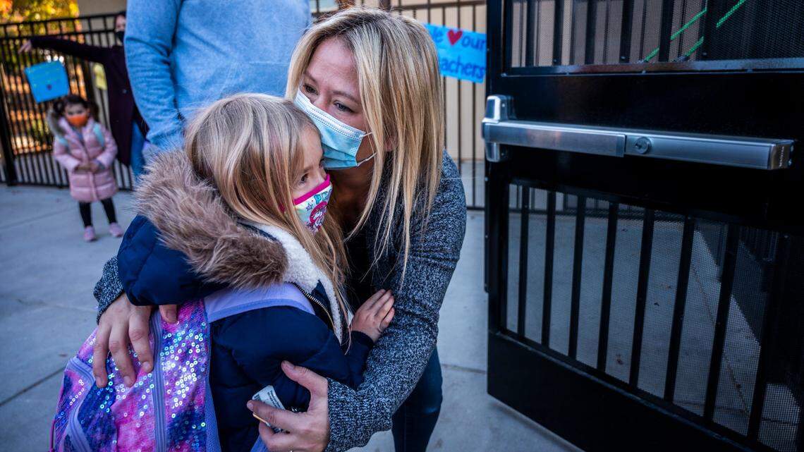Melanie Ely kisses her daughter Madison, a kindergartener at Folsom Hills Elementary School, before she enters the gates to her class on Thursday, Nov. 12, 2020. It was the first day of school for students the Folsom Cordova Unified School District, the largest district in Sacramento County to reopen for in-class instruction. Parents were not allowed to step foot onto campus due to coronavirus protocols.