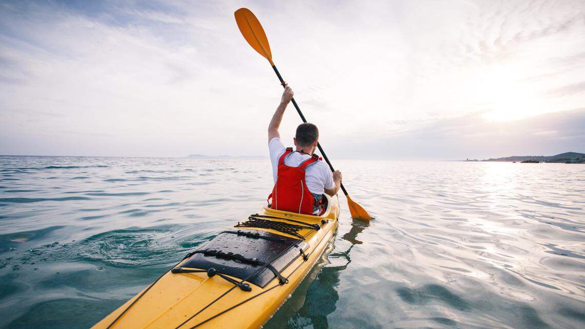 Rear view of man kayaker paddling.
