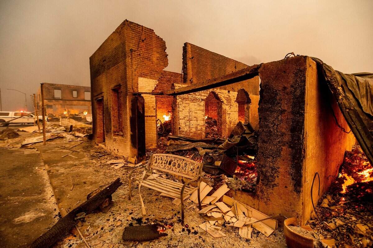 A bench stands outside a scorched building as the Dixie Fire tears through the Greenville community of Plumas County, Calif., on Wednesday, Aug. 4, 2021. The fire leveled multiple historic buildings and dozens of homes in central Greenville. (AP Photo/Noah Berger)
