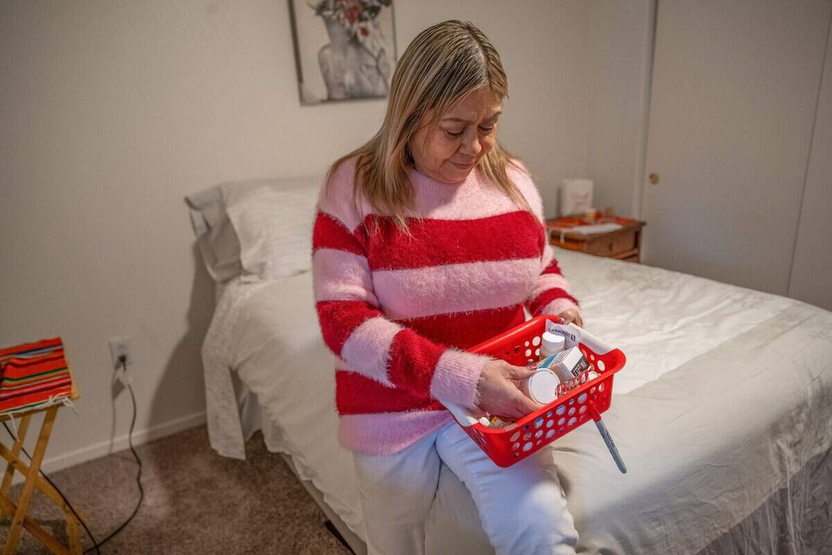 Dolores Mora, 58, sits on a bed donated by United Way as she looks over her daily medications last month at her Natomas apartment. The medications help her with depression, back pain and her years of alcoholism. The grandmother of seven said she feels stable and can now start to enjoy her family after moving to a safer housing situation.