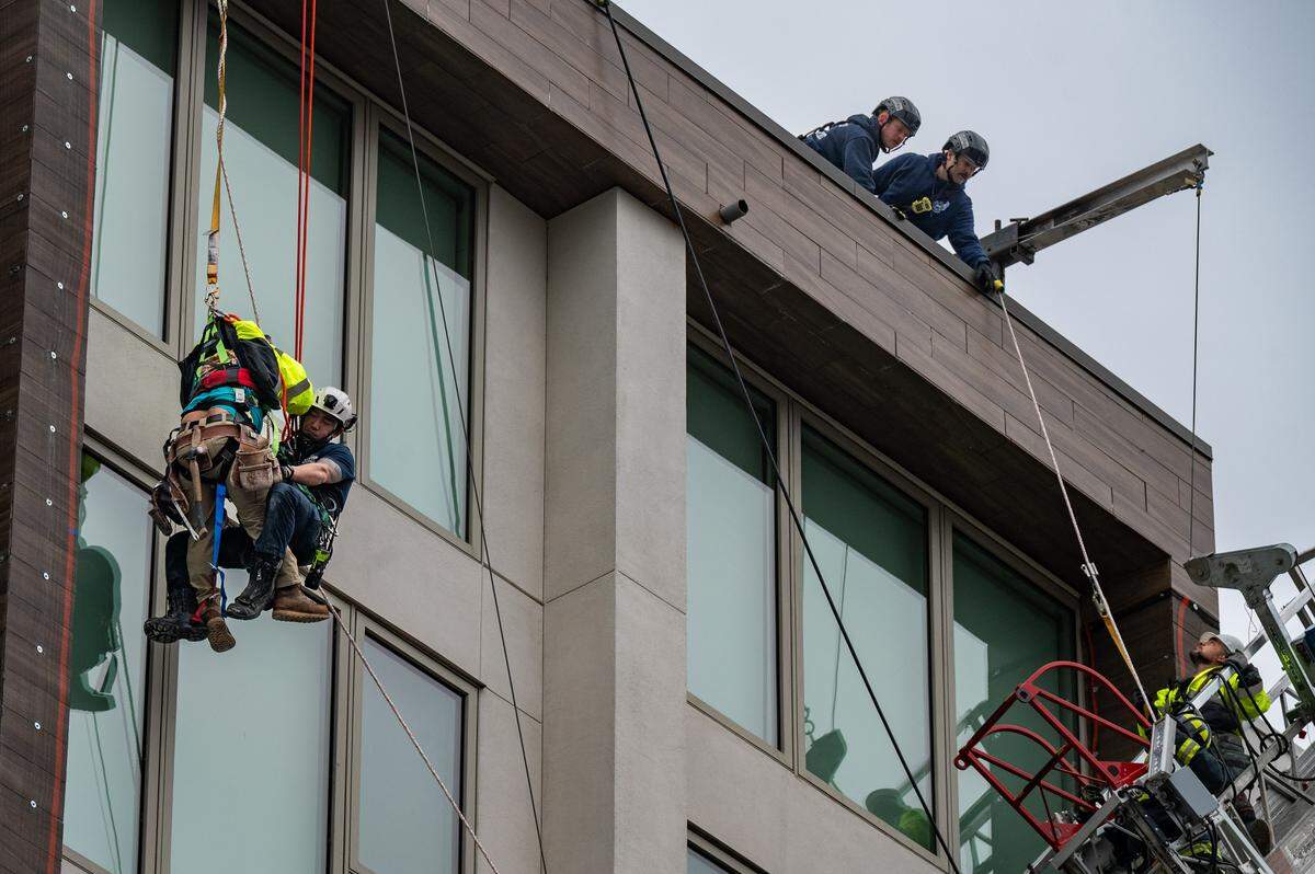 A dangling construction worker, far left, is rescued by a Sacramento firefighter as the second worker, awaiting rescue in a hanging scaffold at far right, communicates with firefighters on the roof the building at 15th and Q streets on Wednesday.