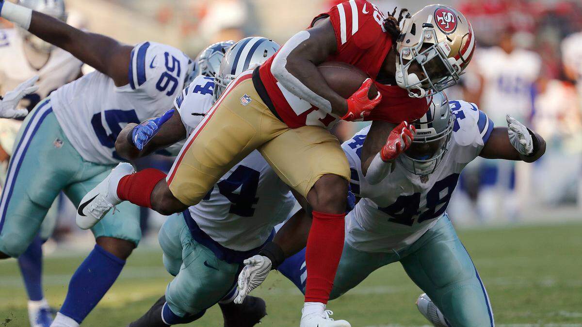 San Francisco 49ers running back Jerick McKinnon, foreground, carries against Dallas Cowboys defensive end Datone Jones (56), linebacker Jaylon Smith, center left, and linebacker Joe Thomas (48) during the first half of an NFL preseason football game in Santa Clara, Calif. McKinnon has injured his knee in practice and could be facing a serious injury.