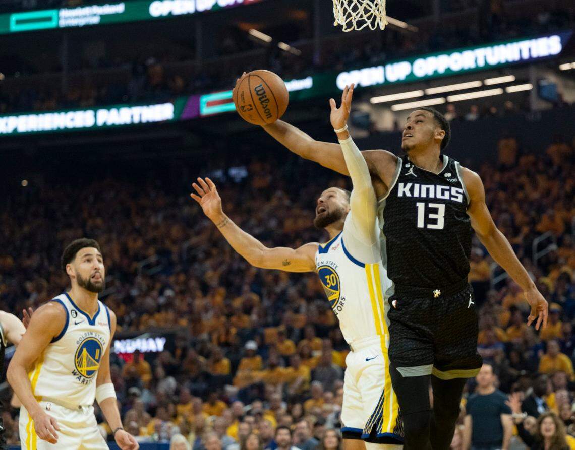 Sacramento Kings forward Keegan Murray dunks the ball around Golden State Warriors guard Stephen Curry during Game 4 of the first-round NBA playoff series at Chase Center in San Francisco on Sunday.