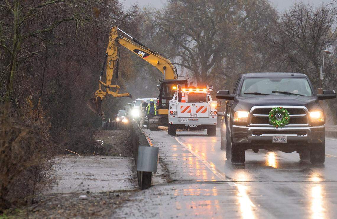 Emergency personnel work to clear debris on Wilton Road at Cosumnes River as water reaches its flood stage amid heavy rainfall Saturday.