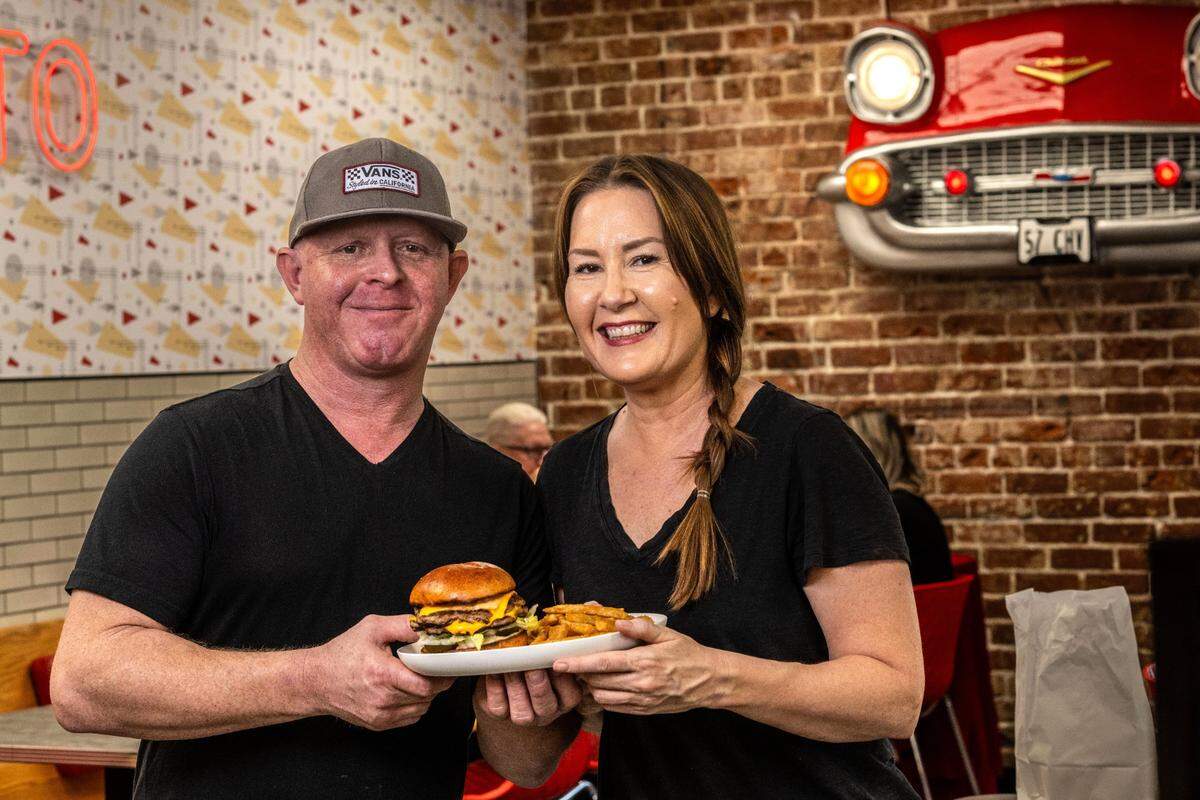 Lucky’s Drive-In co-owners Mike Feagins and Willow Eskridge hold their specialty burger and fries at their Curtis Park restaurant on Thursday, March 6, 2025.