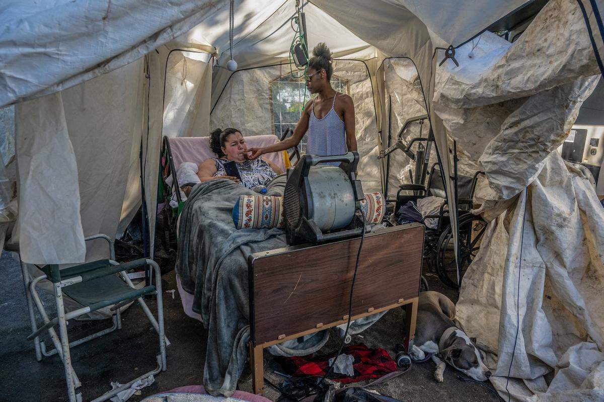 Feeling stressed Holly Porter, who says she rarely smokes, takes a drag off of Monica Gonzales’ cigarette inside a makeshift tent at Camp Resolution on June 21. She said she was stressed about still not getting housing. Earlier that morning the quadriplegic had a visit from Sacramento Mayor Darrell Steinberg and she said he told her to call him directly if she didn’t get housed.