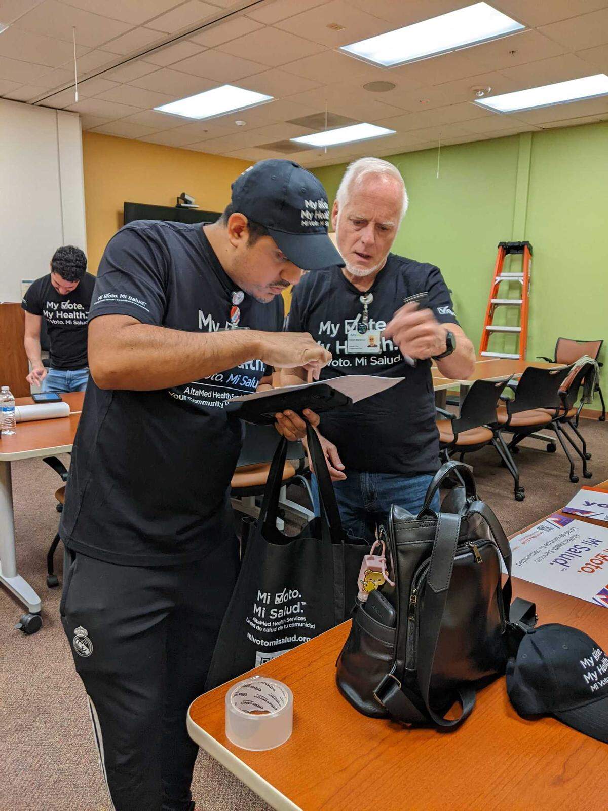 Jonathan Flores, left, an AltaMed Health Services canvasser, and Robert Blackmon, a data analyst in AltaMedâs civic engagement department, discuss the dayâs work before Flores heads out to knock on doors in the surrounding neighborhood.