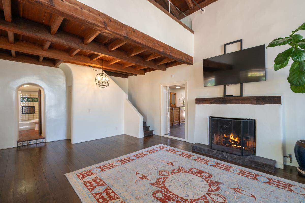 Warm adobe walls and gently arched windows create a cozy living room that captures the inviting spirit of California’s historic interiors.