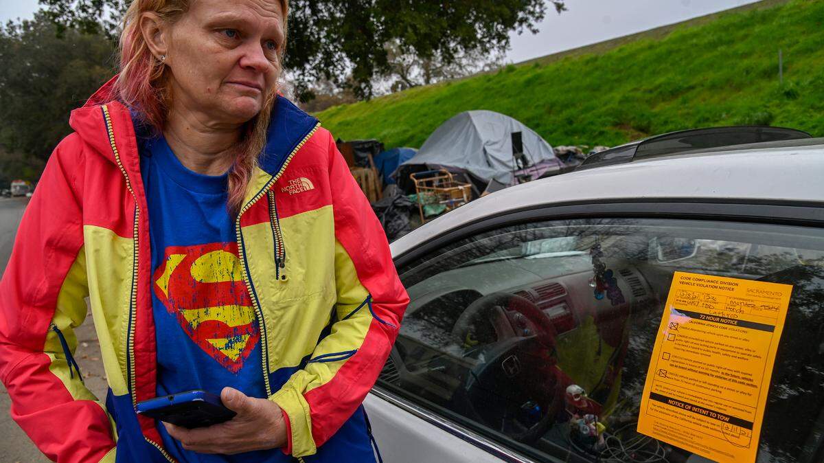 Homeless mom Alice’a Stanley’s eyes fill with tears as her car was tagged by city crews along Lathrop Way in Sacramento on Wednesday, Dec. 8, 2021. Another car that she was going to sell was towed on Monday. “It’s got another tow tag on it and I moved it when they wanted it moved. I have pneumonia and I can’t walk very far. It’s legally registered. I don’t know what to do. They want me to get my stuff out of here and I have to have a way to move it. It’s my only means of transportation, they took my other car,” said Stanley.