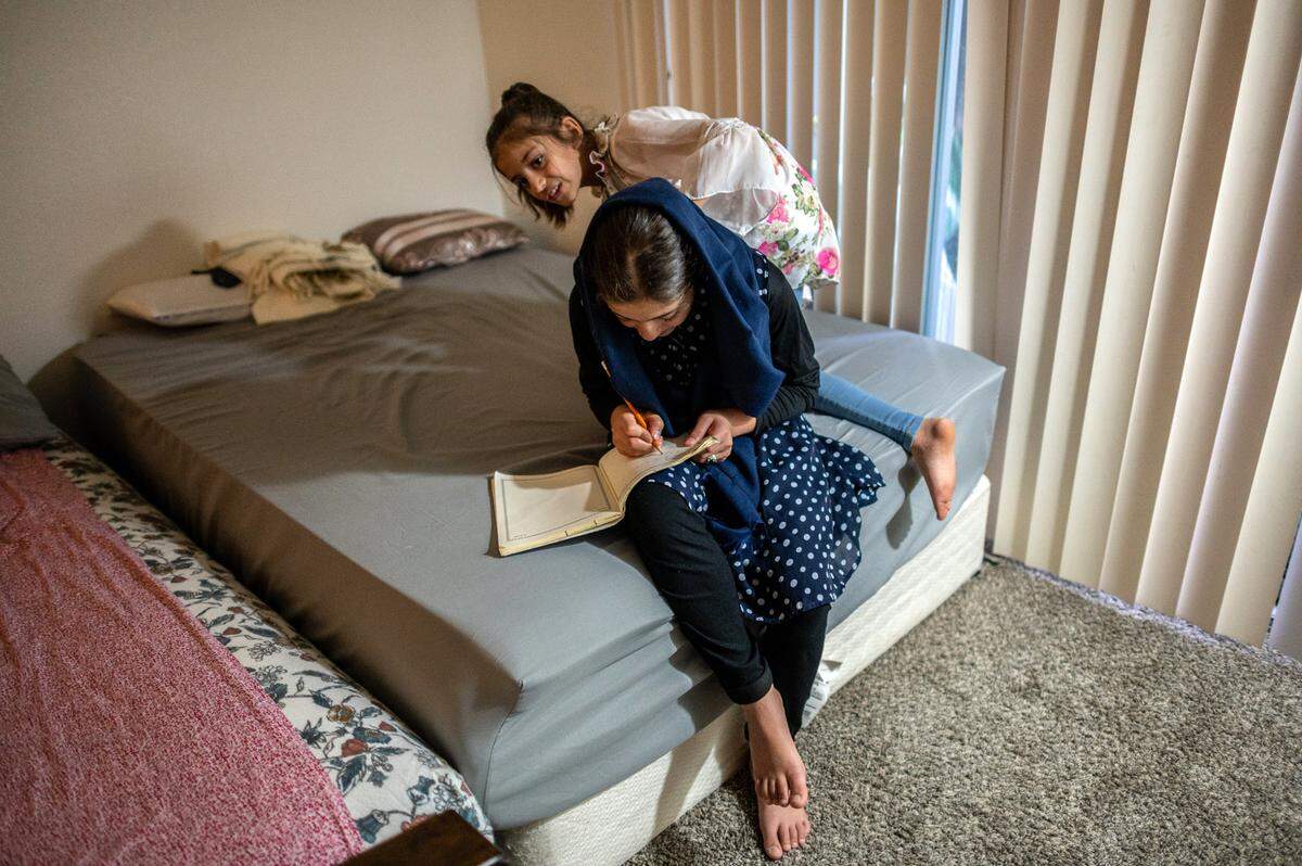 Afghan refugee Zalaikha, 13, practices writing her name in English as her sister Hasiba, 8, peeks over her shoulder. After moving from a budget motel, the family was able to find an apartment in the complex where they were staying with relatives. The four sisters share one of the apartment’s two bedrooms. The other bedroom is shared their 4-year old brother and their parents, and their oldest brother sleeps on a couch in the living room.