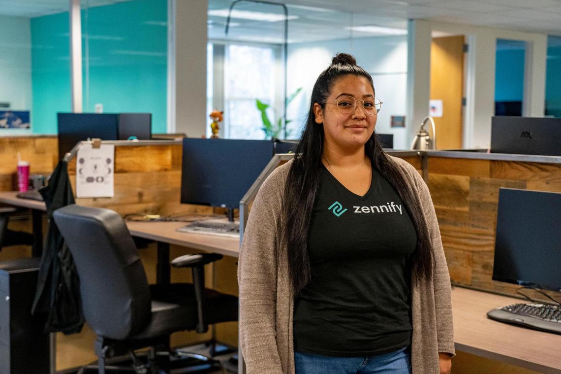 Alicia MacHale, of Sacramento, stands near her desk inside Zennify’s offices on Friday, Jan. 22, 2021. MacHale recently started working at the Sacramento IT consulting firm as an apprentice after graduating Sacramento’s digital upskilling program last year.