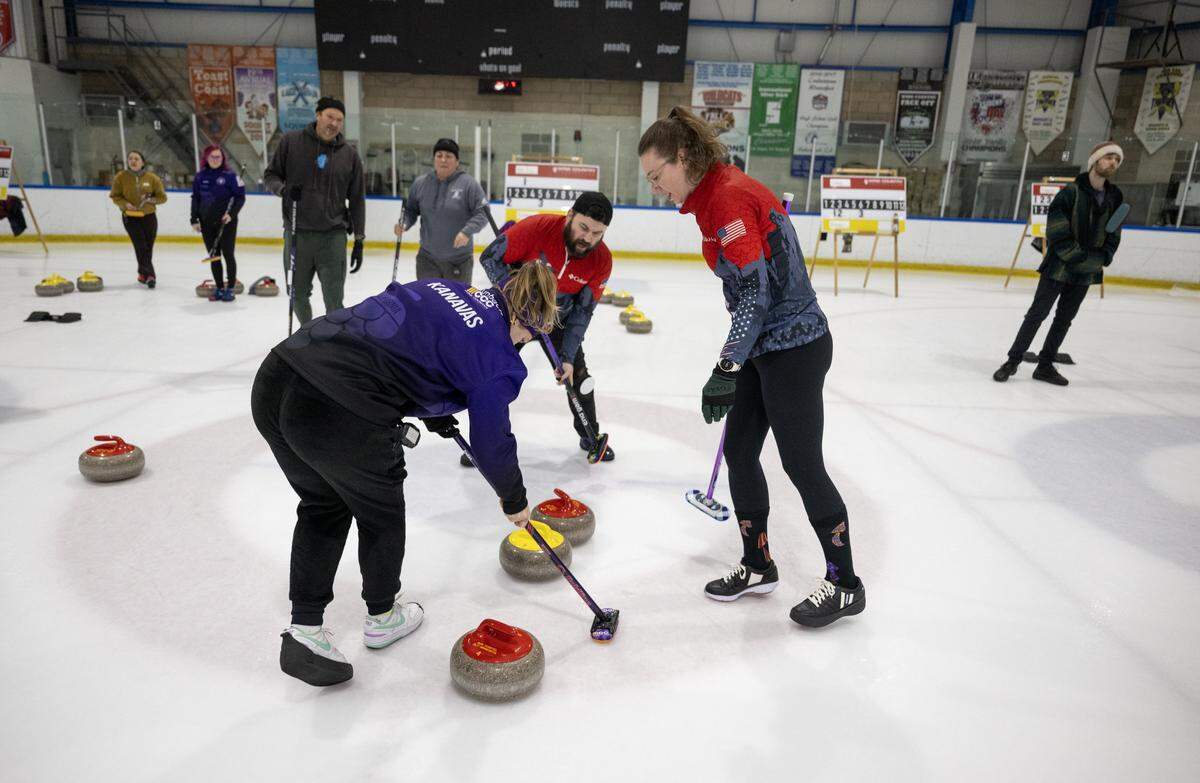 Eran Foley and Zoe Kanavas sweep in front of the curling stone during a match earlier this month at Skatetown Ice Arena in Roseville.