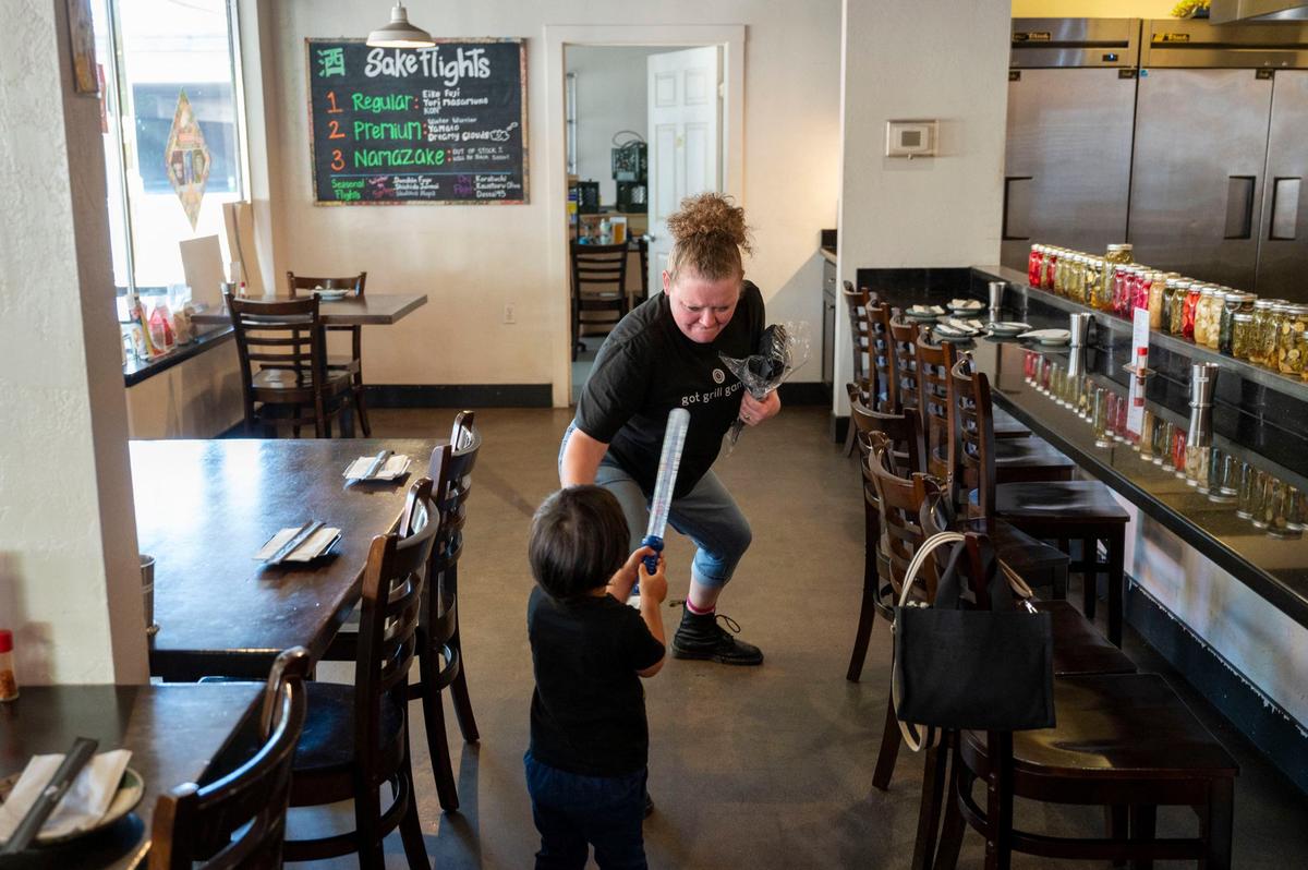 Toki Sawada’s youngest son, Yoshi Takehara, 3, holds up a light saber toy while playing with restaurant staff Lexi Crook on Wednesday at Binchoyaki.