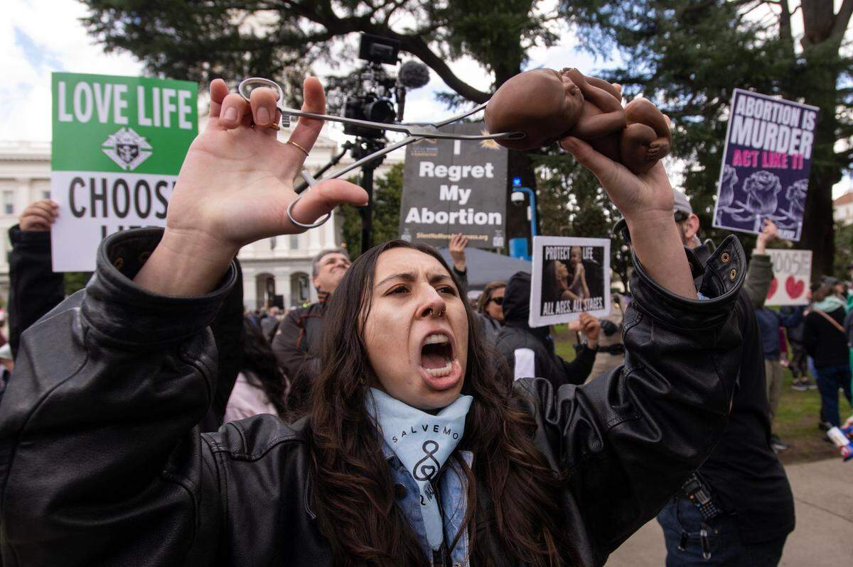 Abortion opponent Melanie Salazar of Pro Life San Francisco holds a fake fetus and forceps as she yells at abortion-rights supporters during the 2023 California March For Life at the state Capitol in Sacramento on Monday, March 6, 2023.