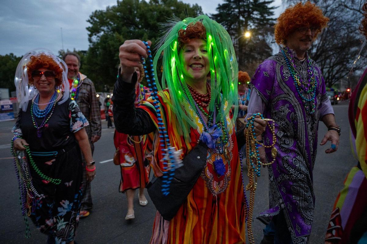 Noreen Berson of the Mrs. Roper Sacramento group hands out beads at the City of Trees Parade celebration of Mardi Gras on Saturday.