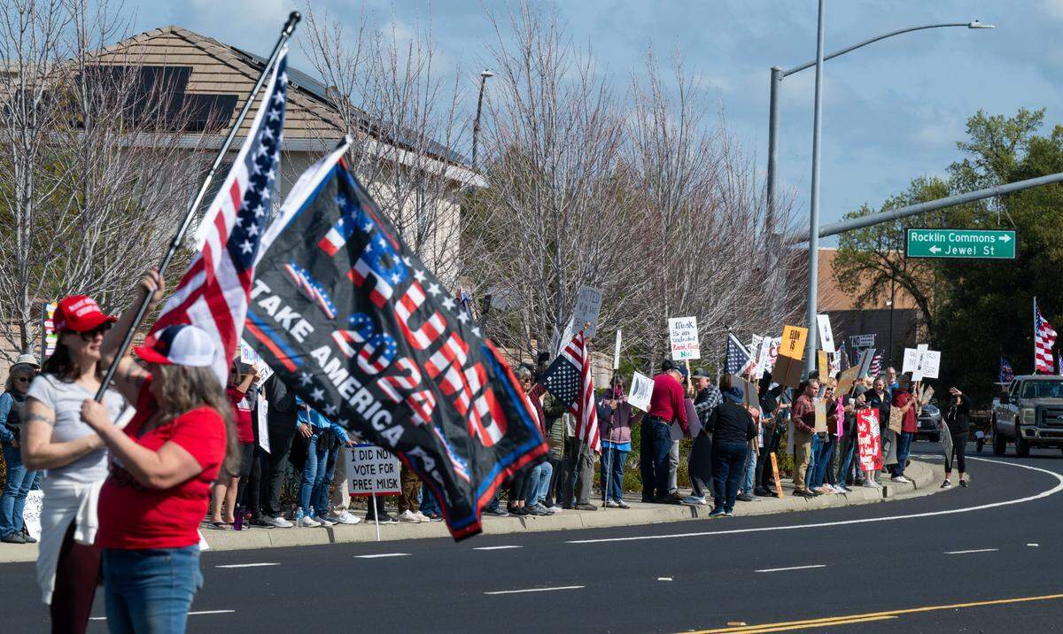 MAGA counter protesters wave Trump and American flags in the center lane of Granite Drive in Rocklin as anti-Tesla protesters line the street across from the Tesla dealership on Saturday, March 29, 2025.