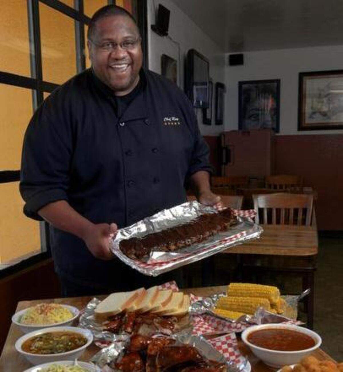 Rodney Ray holds a full slab of ribs and displays other meats and sides at his Taste of Texas BBQ in Sacramento in 2013.