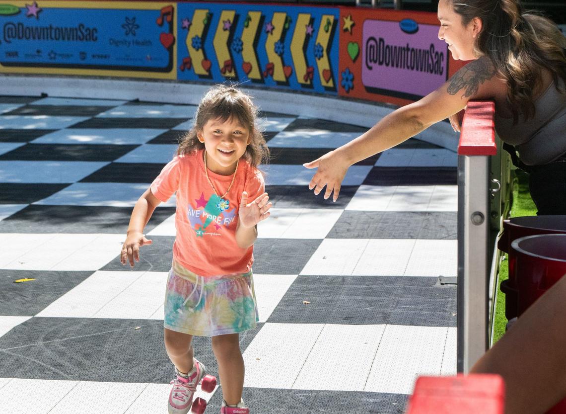 Isabella Cebrero, 5, left, gives her mom, Yatzeni Cebrero, a high five as she completes a lap around the Downtown Roller Rink in downtown Sacramento’s Ali Youssefi Square on Friday, June 28, 2024. The young roller skater took periodic breaks during her time at the rink to sit at a nearby picnic table in the shade with her mom.