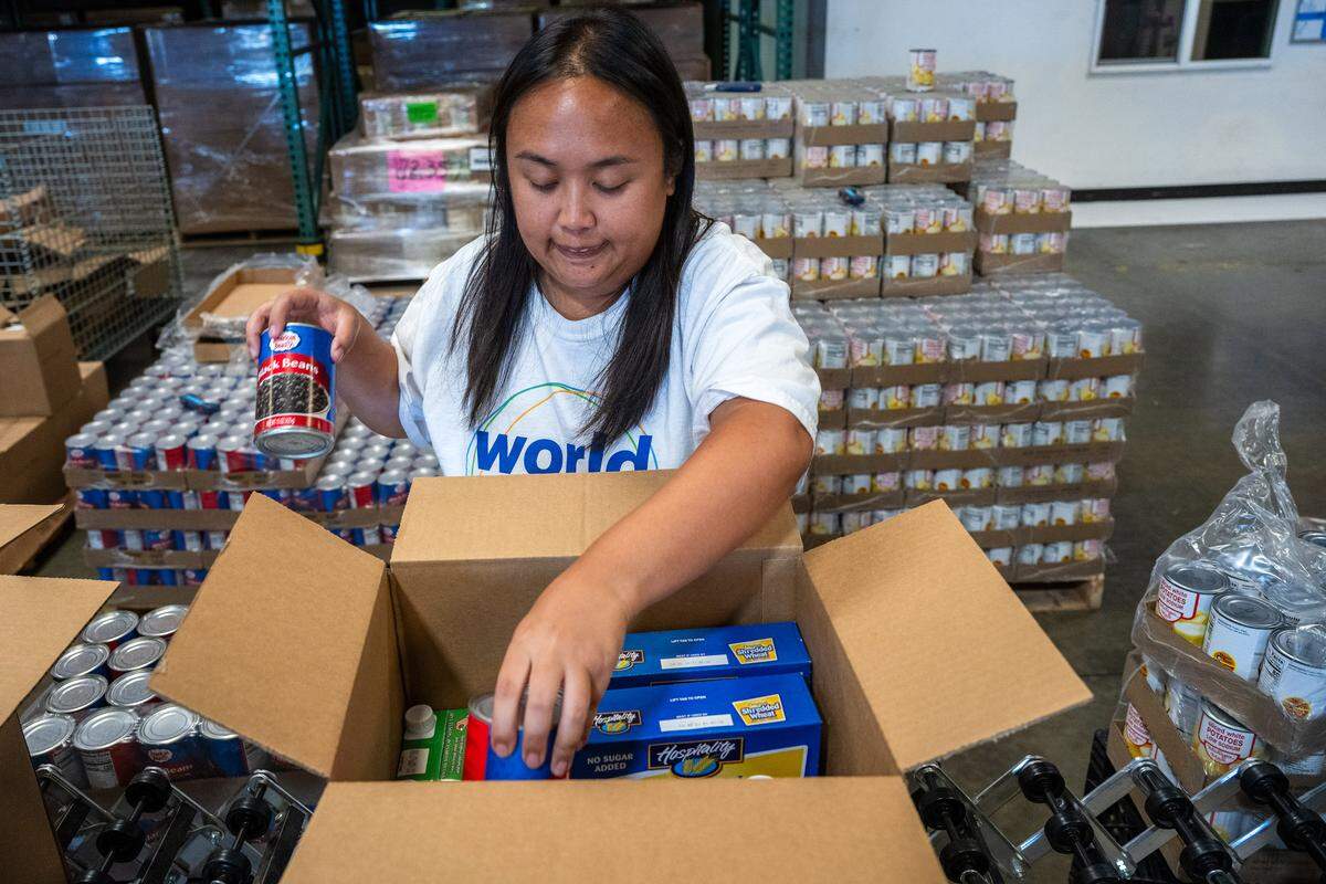 Volunteer Rochelle Araga adds a can of beans to a box of food in October that will be distributed to a senior at the Sacramento Food Bank & Family Services. Federal cuts will for the state to pay billions more to maintain programs like CalFresh at its current level. 