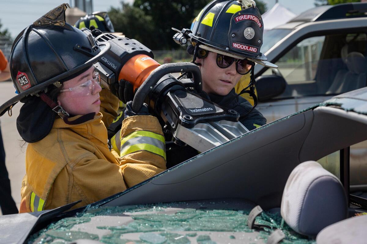 Desiree Goldthorpe, 17, is assisted with the Jaws of Life by Madelyn Steele of the Woodland Fire Department to remove a rear car door during the HERo Girls Fire Camp, hosted by the Cosumnes Fire Department, on Sunday.