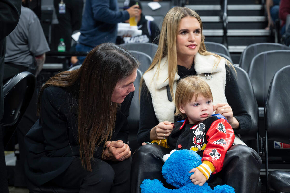 Shashana, right, holds her son Tiger, 1, as she watches her husband Sacramento Kings forward Domantas Sabonis (10) warmup and her mother Tiffany talks with Tiger before the NBA basketball game against the Minnesota Timberwolves on Saturday, Dec. 23, 2023, at Golden 1 Center.