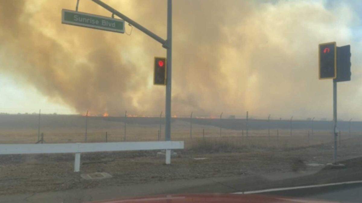Sacramento Metropolitan Fire District firefighters extinguish flames spreading through a field in Rancho Cordova on Monday near Douglas Road and Sunrise Boulevard.