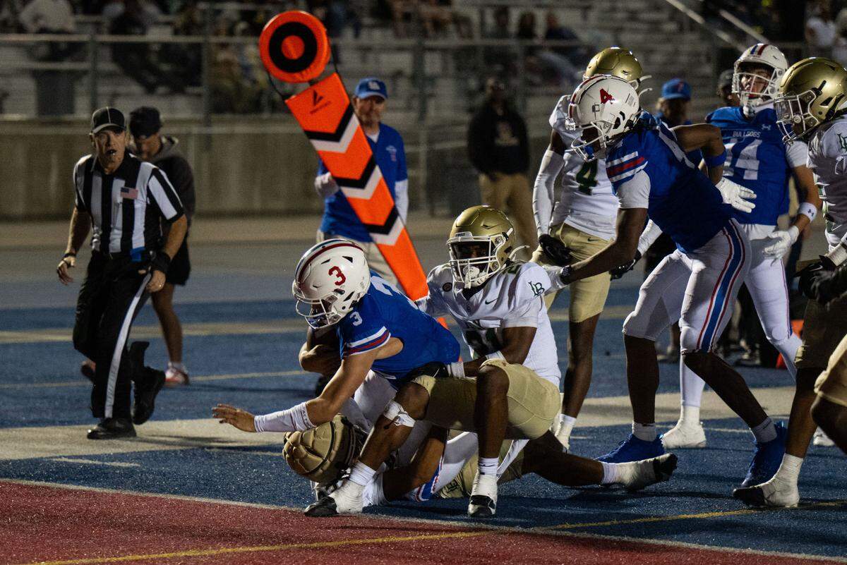 Folsom Bulldogs quarterback Ryder Lyons (3) drags multiple Long Beach Poly defenders into the end zone after a 16-yard scramble in the second quarter on Friday, Aug. 23, 2024.