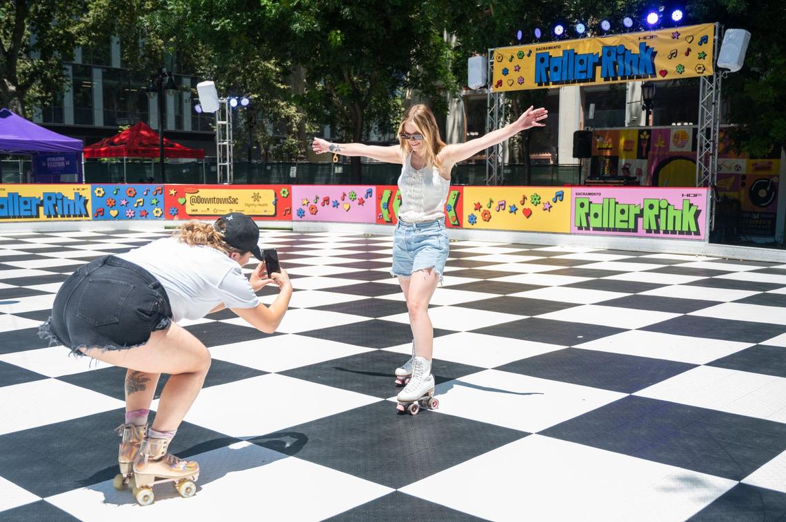Quincy Gonzalez, left, takes a photo of Devonna Valvoda in the middle of the Downtown Roller Rink in downtown Sacramento’s Ali Youssefi Square on Friday, June 28, 2024. Valvoda, who hasn’t skated in nearly two decades, said it was her favorite activity as a kid.