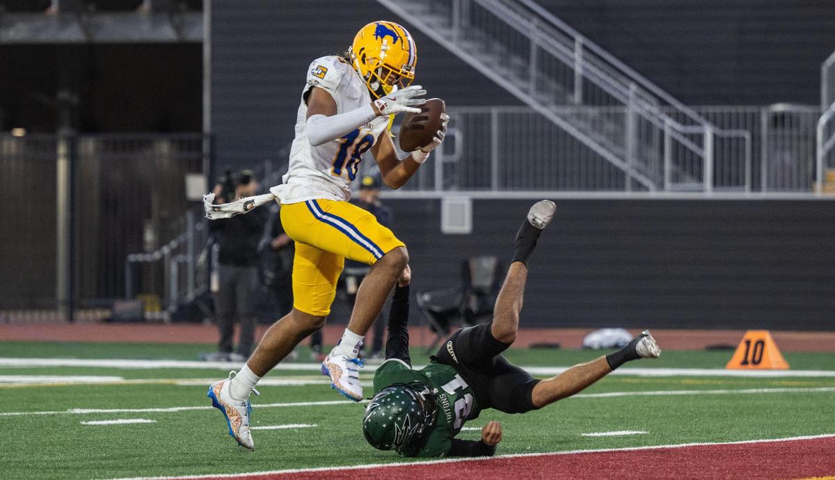 The Grant Pacers’ Zo Edwards (18) runs in for a touchdown over the Pacifica Tritons’ Deon Hasley (21) during the CIF State Division 2-AA championship at Saddleback College in Mission Viejo on Friday.