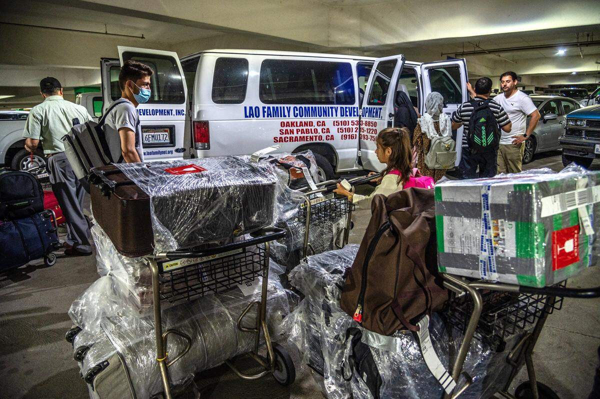 With the possessions that his family had managed to bring from Afghanistan on carts, Abdul chats with Naimantullah Sultani, far right, of the resettlement agency Lao Family Community Development, which picked up the family at Sacramento International Airport on Aug. 16. Sultani came to the U.S. from Afghanistan with Special Immigrant Visa in 2019.