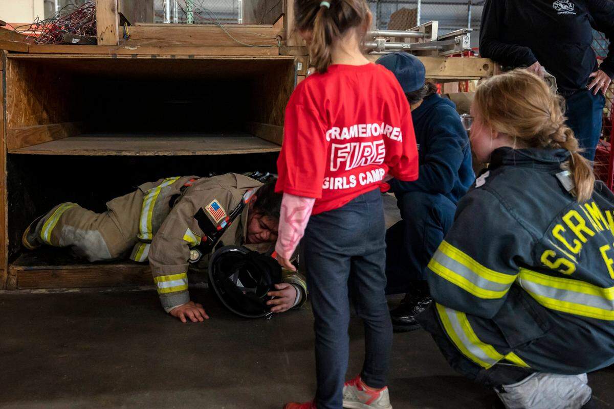 Samatha Velasco-Murillo, 17, of Sacramento, crawls out of the confidence course to instructors and other campers at the Sacramento Area Girls Fire Camp at McClellan Park on Saturday, Oct. 23, 2021. The activity is a pitch black course for the campers to crawl through with as much gear as they were comfortable wearing.